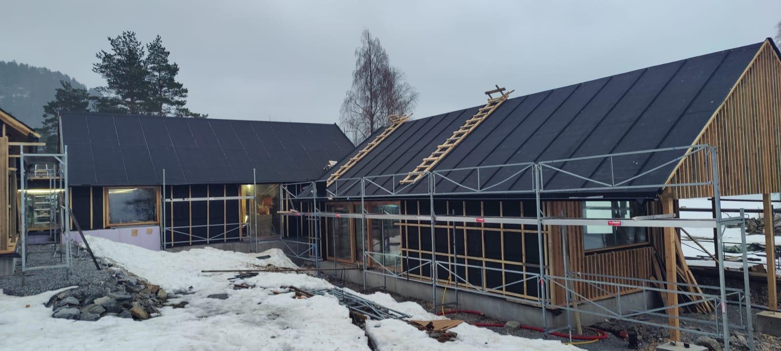 Bygg i snø med stillas og nytt mørkt tak med profiler